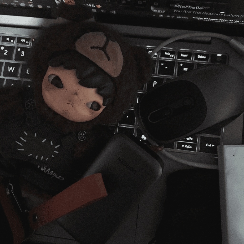 Jaycee's desk at night: a plush toy resting on a backlit laptop keyboard beside a wireless mouse